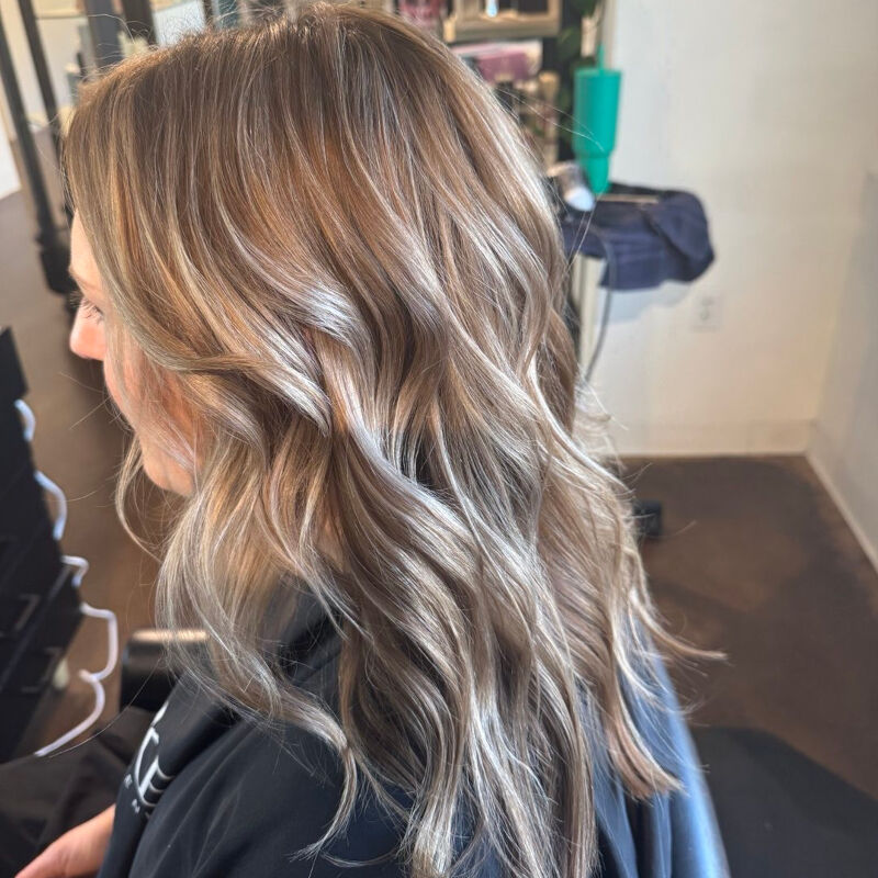 Wavy hair with creamy lived-in blonde balayage over a soft root